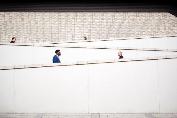 Graphic Shot Of Commuters Walking To Work Along Concrete Walkway Outside Building