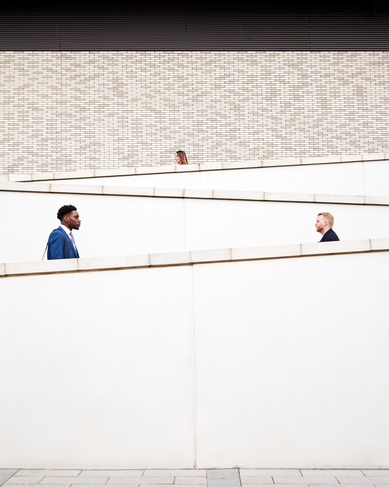 Graphic Shot Of Commuters Walking To Work Along Concrete Walkway Outside Building