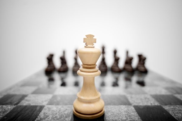 The general before the battle field. The meaningful photo of chess king staying before the set of another colour pieces.
